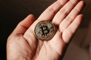 A person holding a shiny Bitcoin token in their open hand.