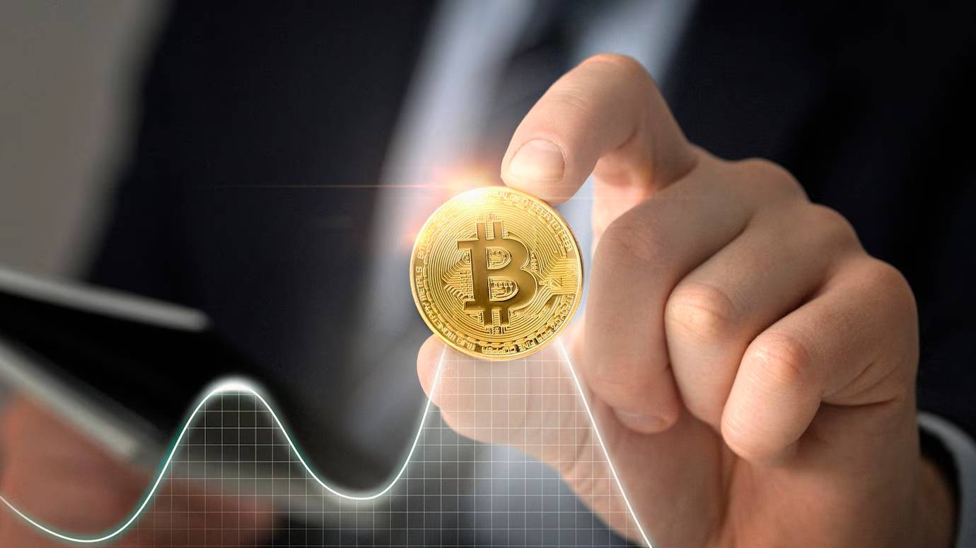 A person in a suit holding a Bitcoin, with a digital graph line in the background.