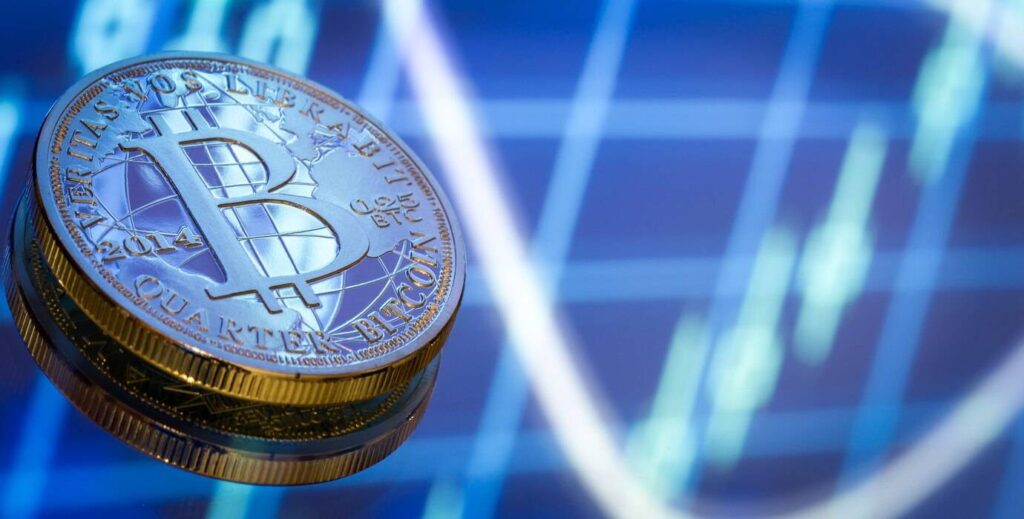 A stack of Bitcoin coins against a blurry stock market graph background.