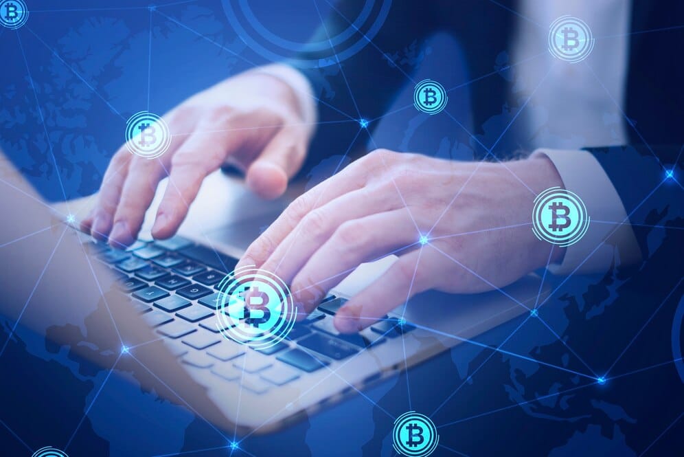 Person using a laptop with Bitcoin cryptocurrency symbols and digital network graphics overlay.