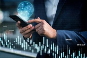 Businessman using smartphone with digital hologram of a global network and stock market data overlay.