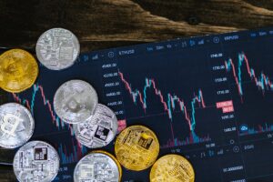 Various cryptocurrency coins on a tablet displaying live trading charts of digital currency markets.