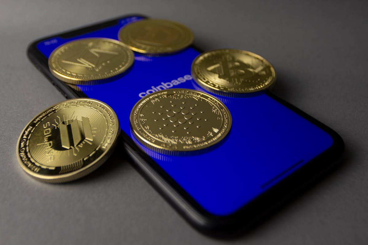 Gold cryptocurrency coins on a blue smartphone with a Coinbase logo.